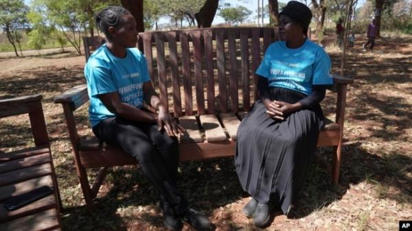 Siridzayi Dzukwa, a grandmother, right, talks to a colleague while seated at a bench in Hatfcliffe on the outskirts of the capital Harare, Zimbabwe, May 11, 2024.
