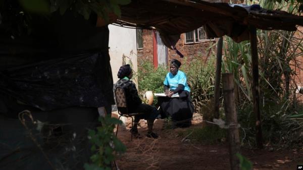 Siridzayi Dzukwa, right, talks to Tambudzai Tembo outside her house near Harare, Zimbabwe, May 15, 2024. In Zimbabwe, talk therapy involving park benches and a network of grandmothers has become a saving grace for people with mental health issues.
